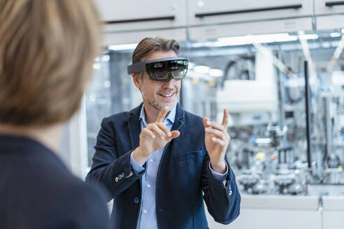 Businessman with AR glasses and businesswoman in a modern factory - DIGF07244