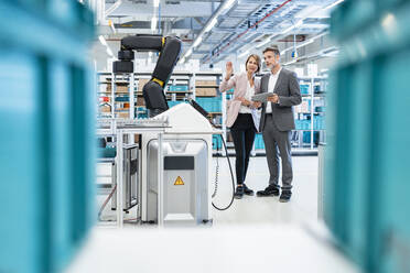 Businessman and businesswoman talking in a modern factory hall - DIGF07298