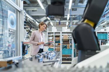 Businesswoman with tablet in a modern factory hall - DIGF07303