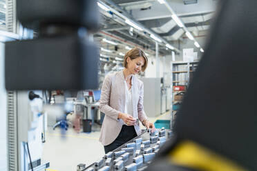 Geschäftsfrau bei der Prüfung von Werkstücken in einer modernen Fabrikhalle - DIGF07305