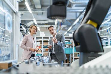 Businessman and businesswoman talking in a modern factory hall - DIGF07313