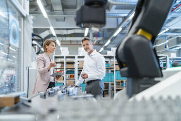 Businessman and businesswoman talking in a modern factory hall - DIGF07314