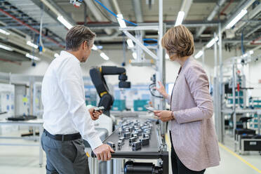 Businessman and businesswoman talking in a modern factory hall - DIGF07318