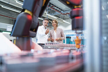 Businessman and businesswoman talking in a modern factory hall - DIGF07321