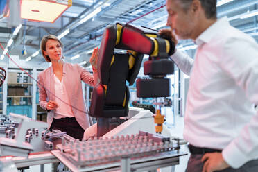 Businessman and businesswoman talking in a modern factory hall - DIGF07336