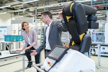 Businessman and businesswoman talking in a modern factory hall - DIGF07349