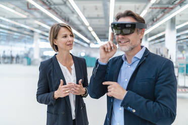 Businessman with AR glasses and businesswoman in a factory hall - DIGF07365