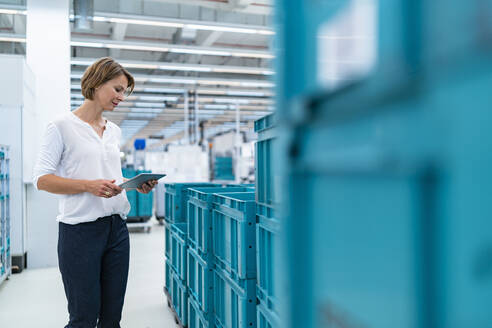 Businesswoman with tablet in a factory hall - DIGF07368