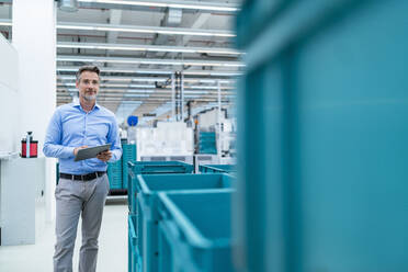 Businessman with tablet in a factory hall - DIGF07369