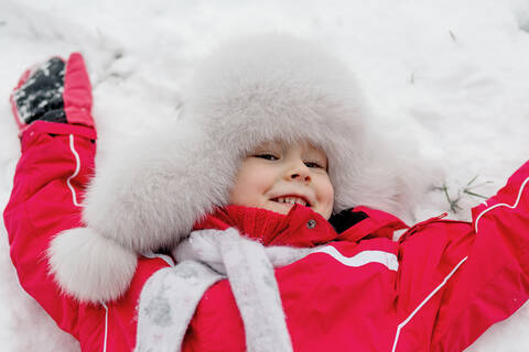 Smiling girl lying in the snow stock photo