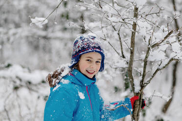 Smiling girl shaking a snowy tree - OGF00018