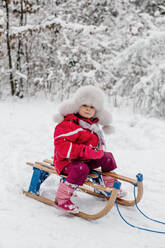 Das Kind sitzt auf den Schlitten im winterlichen Wald - OGF00019