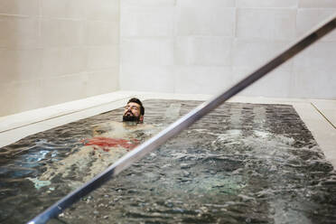 Man floating in a whirlpool in a spa - LJF00391