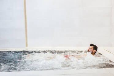 Mann im Whirlpool in einem Thermalbad - LJF00393