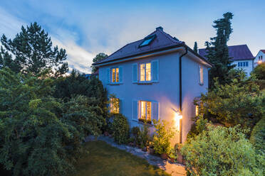 Deutschland, Baden-Württemberg, Stuttgart, Außenansicht eines Hauses im Garten in der Abenddämmerung - WDF05324