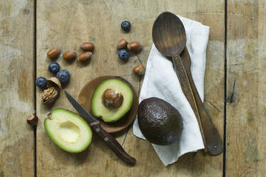 Halved avocado, blueberries and nuts on wooden table seen from above - ASF06442