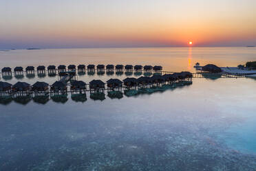 Malediven, Insel Olhuveli, Resort-Bungalows in der Lagune des Süd Male Atolls bei Sonnenuntergang - AMF07150