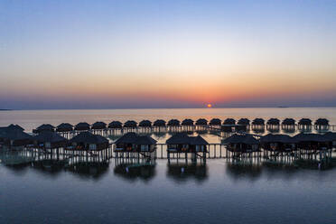 Malediven, Insel Olhuveli, Resort-Bungalows in der Lagune des Süd Male Atolls bei Sonnenuntergang - AMF07153