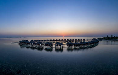 Malediven, Insel Olhuveli, Resort-Bungalows in der Lagune des Süd Male Atolls bei Sonnenuntergang - AMF07154