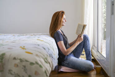 Young woman at home chilling in bedroom and reading a book - AFVF03585