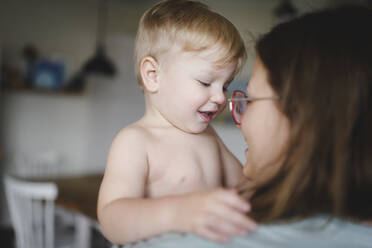 Portrait of happy little boy on his mother's arms at home - EYAF00302