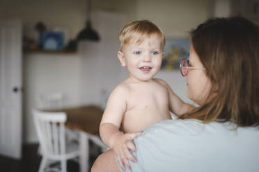 Porträt eines kleinen Jungen in den Armen seiner Mutter zu Hause - EYAF00303