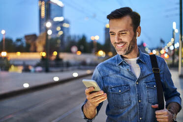 Mann steht mit Smartphone und wartet auf den Feierabendverkehr - BSZF01085