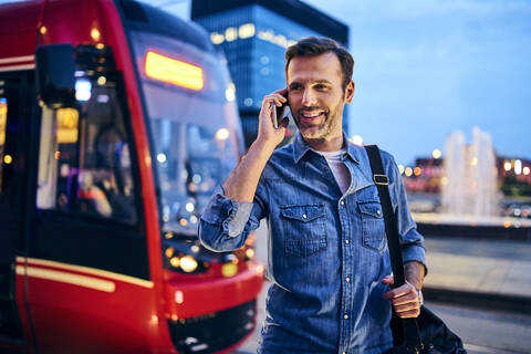 Man making phone call on smartphone with tram in the background stock photo