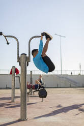 Man doing workout at exercise equipment outdoors - MAUF02647