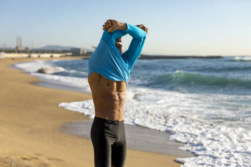 Mann zieht sein Hemd beim Training am Strand aus - MAUF02662