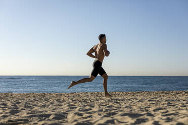 Mann mit nacktem Oberkörper beim Joggen am Strand - MAUF02670