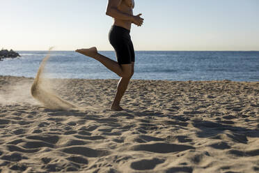 Barechested man jogging on the beach - MAUF02671