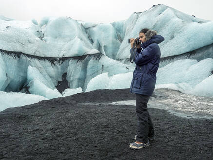 Iceland, man taking photo by Eyjafjallajokull - TAMF01758