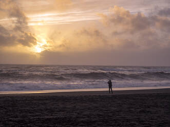 Island, Silhouette einer Person am Reynisfjara Strand - TAMF01760