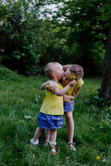 Kleines Mädchen küsst ihre Schwester auf einer Wiese - OGF00029