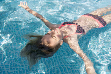 Germany, Brandenburg, Teenage girl floating in pool - BFRF02050