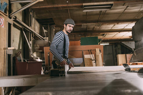 Carpenter at work with wooden board on a saw - VPIF01310