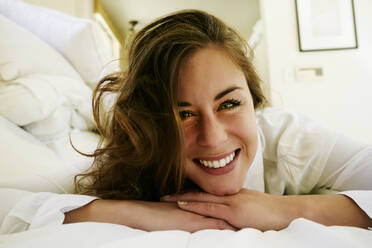 Gemischtrassige Frau lächelnd auf dem Bett - BLEF09497
