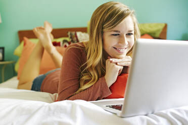 Caucasian woman using laptop on bed - BLEF09549