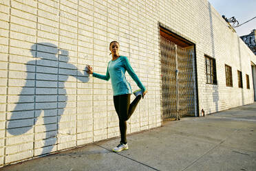 Mixed race athlete stretching on sidewalk - BLEF09567