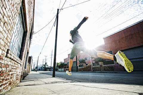 Gemischtrassiger Sportler joggt auf dem Bürgersteig, lizenzfreies Stockfoto