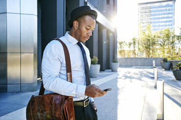 Black businessman using cell phone outside office building - BLEF09590