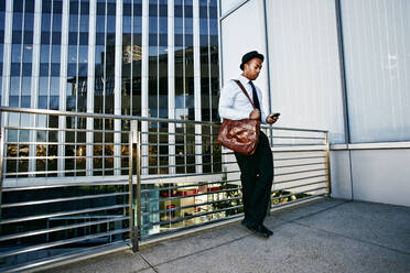 Black businessman using cell phone outside office building - BLEF09603