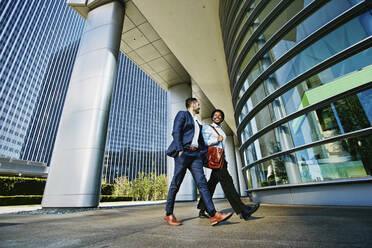 Businessmen walking outside office building - BLEF09616