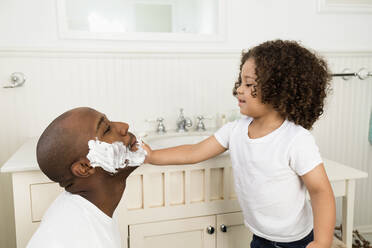 Boy helping father shave in bathroom - BLEF09627