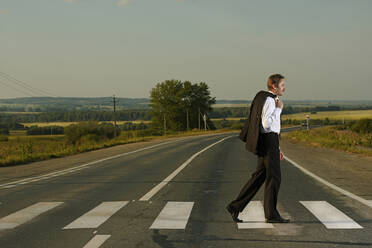 Caucasian businessman crossing rural street - BLEF09640