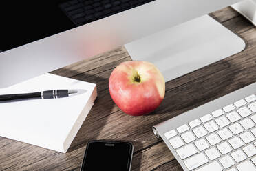 Apple and smart phone on desk below computer - FSIF03952