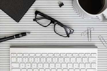 View form above eyeglasses, coffee, pen and paper clips on desk above computer keyboard - FSIF03967