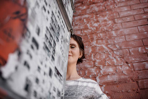 Russland, Moskau, Low angle view of woman standing by brick wall, lizenzfreies Stockfoto