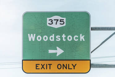 Low angle view of exit road sign at highway against sky - MMAF01072